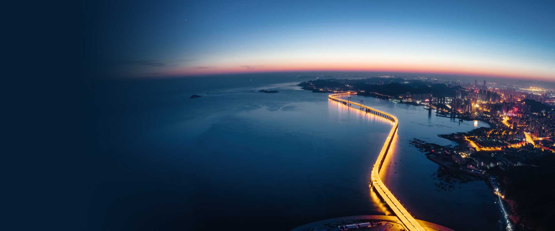 night view of a bridge with lights in middle of ocean