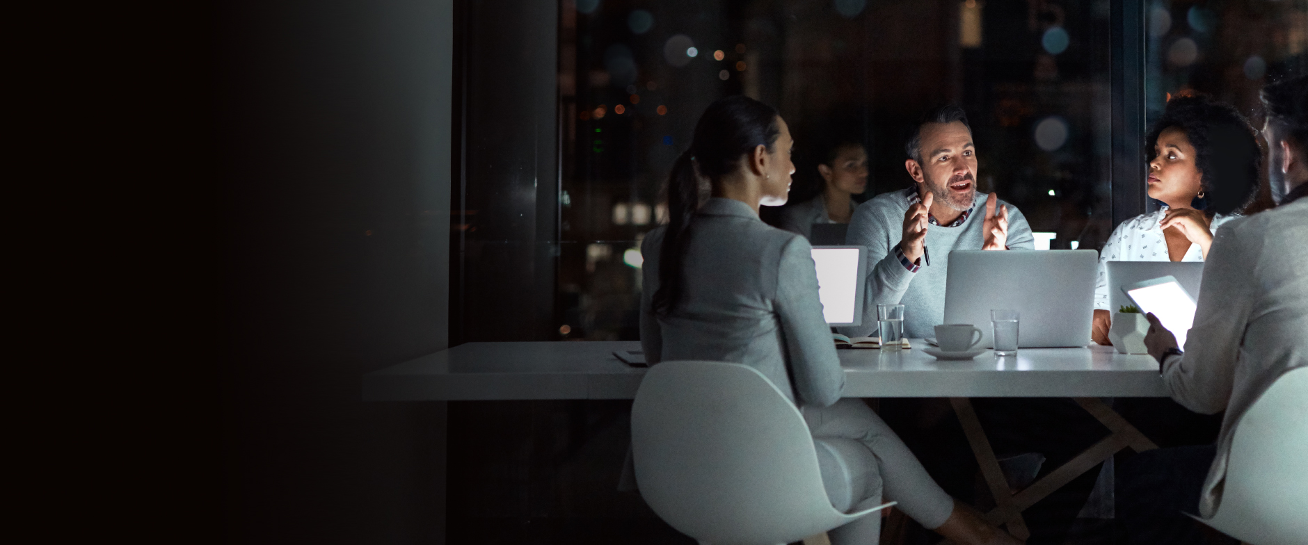 profesionales trabajando por la noche alrededor de un escritorio