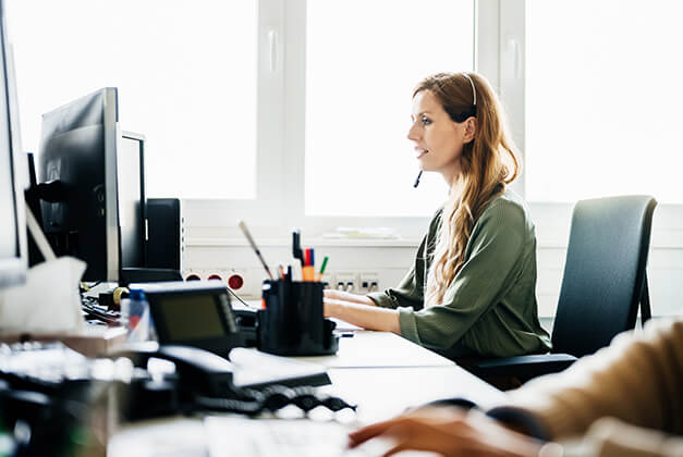 Woman in front of a computer with a headset on.