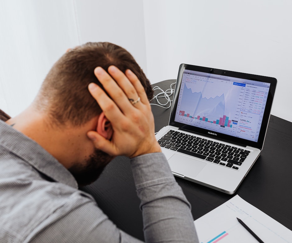 person sitting in front of laptop looking at the chart and stressed