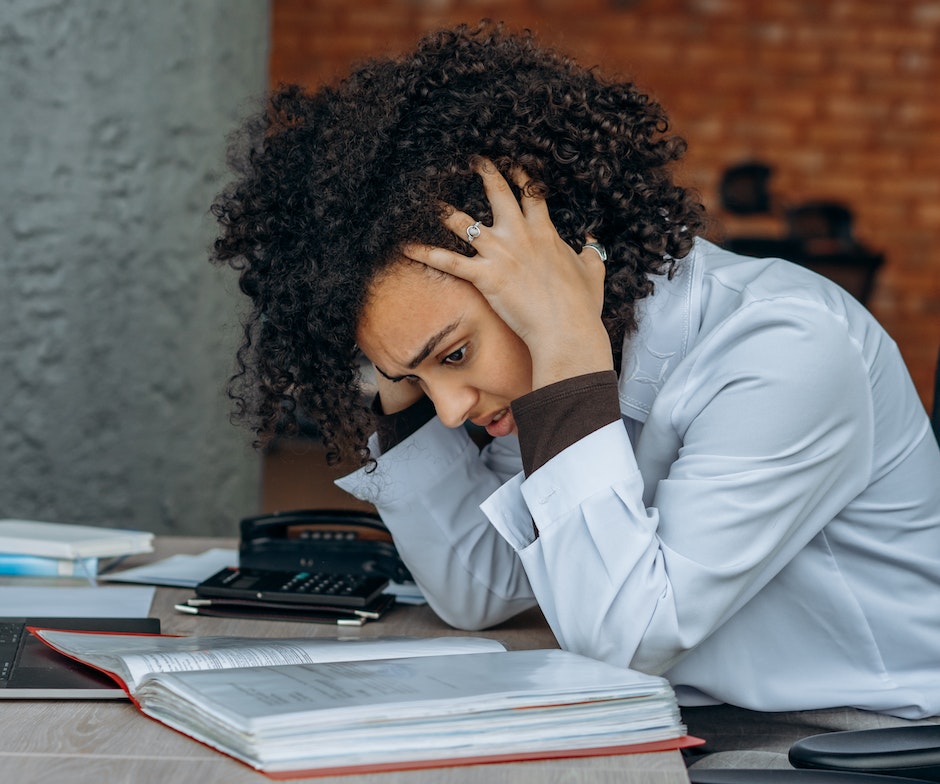 women feeling stressed holding her head in sitting position while reading book 