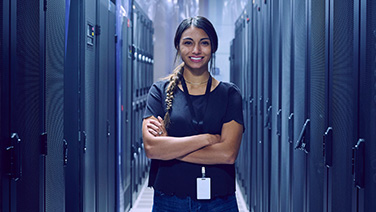 A person standing in between racks of storage systems with their arms crossed