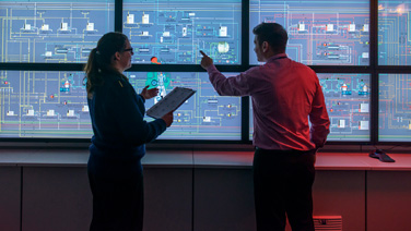 professionals viewing a wall of monitors